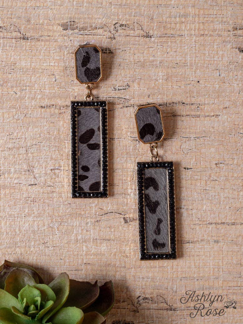 Pair of earrings on a textured beige surface with 'Ashlyn Rose' branding.