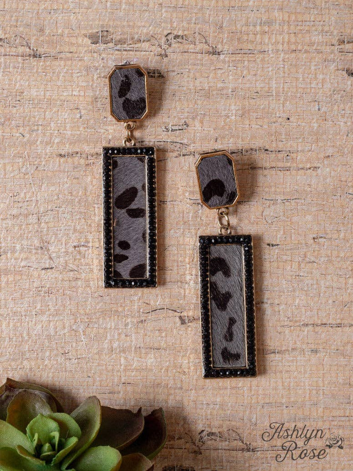 Pair of earrings on a textured beige surface with 'Ashlyn Rose' branding.